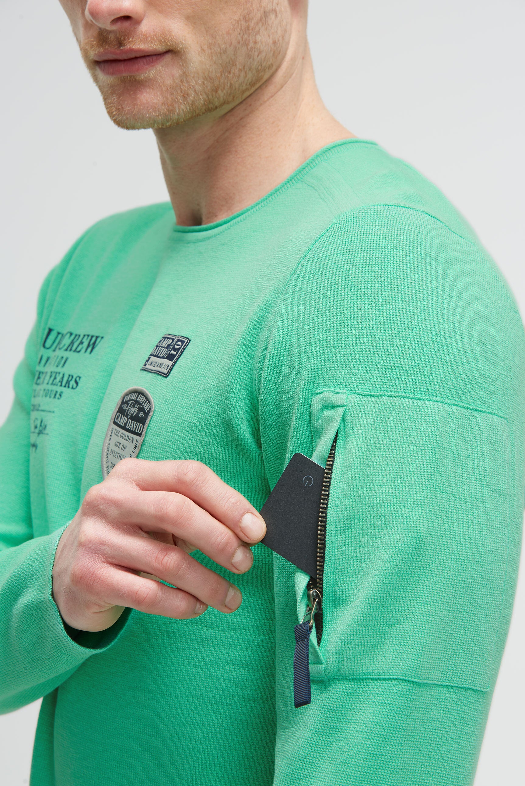 Sweter z nadrukiem, naszywkami i kieszenią na rękawie