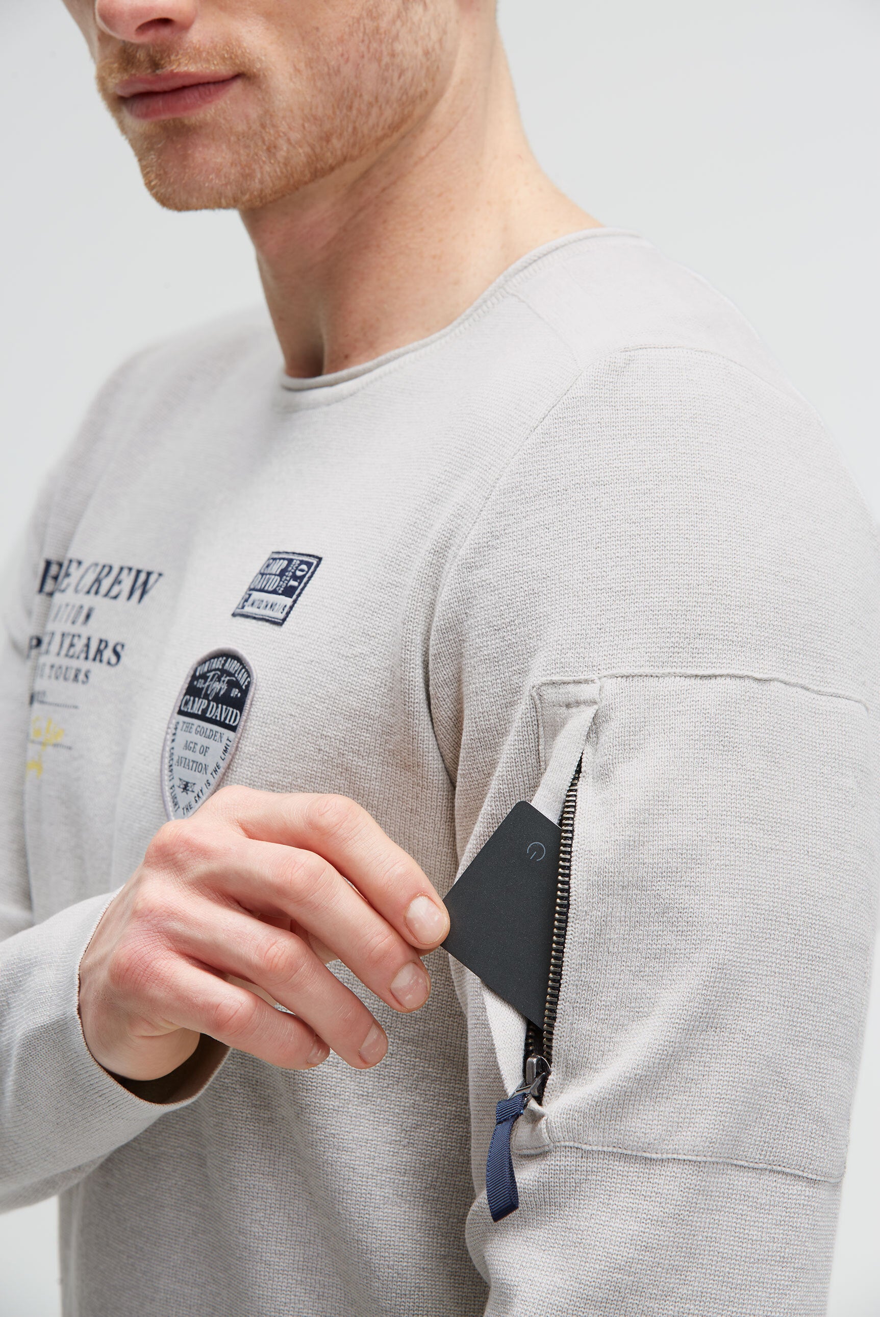 Sweter z nadrukiem, naszywkami i kieszenią na rękawie